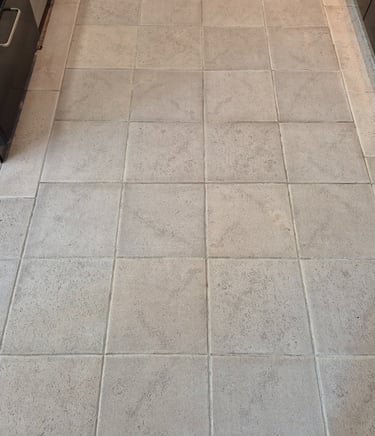 Light gray square ceramic floor tiles in a kitchen after laser cleaning