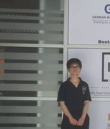 a woman wearing IMI certified shirt infront of window