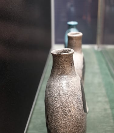 3 ceramic vessels in a row, shaped as historic 'pilgrim flasks' with pale pink raku glaze