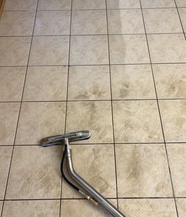 Tile and grout cleaning using a high-pressure wand showing clear before and after floor results.