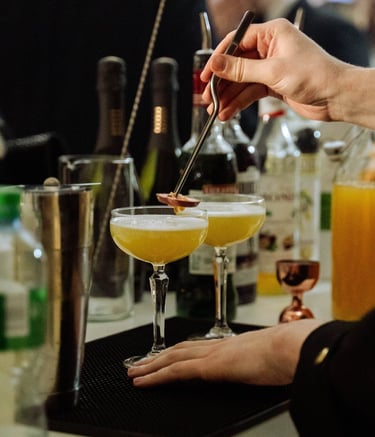 Profesionalus barmenas preciziškai ruošia kokteilį elegantiškame vakarėlyje