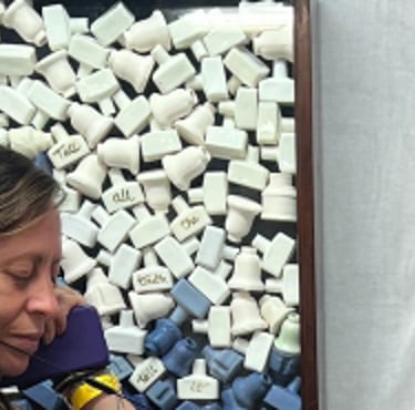 2 visitors listen to an audio installation, looking at a sculpture of Victorian ink bottles