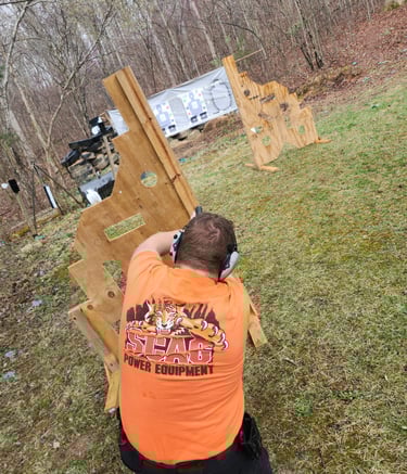 Kneeling man engaging targets from a barrier using self-defense firearm during training.
