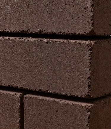 Close-up detail of premium dark brown clay bricks with a fine, granular texture. The image uses professional lighting to emphasize the material's durability and precision firing. North American architectural style.