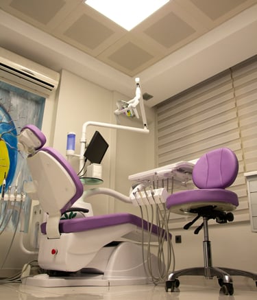 Modern dental clinic room with a purple examination chair and professional equipment.