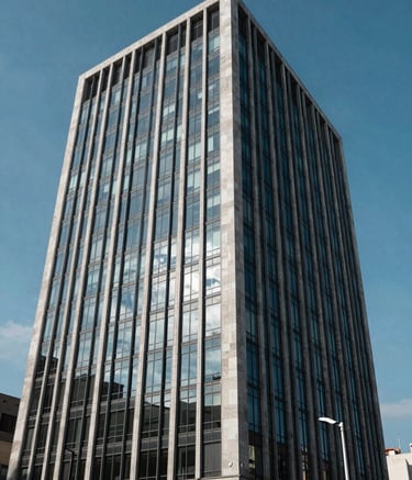 A professional architectural photograph of a modern corporate office building in Bogotá, reflecting the blue sky, symbolizing the stability and reliability of professional energy services.
