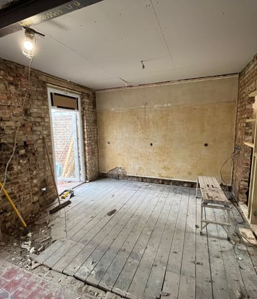 a room with a wooden floor and a brick wall in need of renovation
