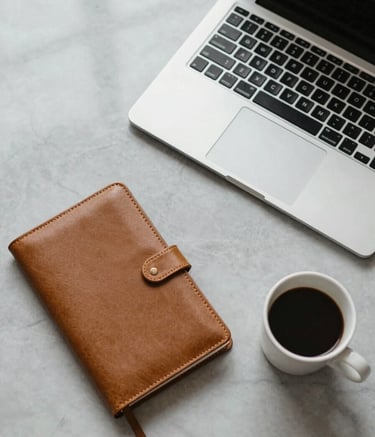 A top-down, clean photography shot of a sleek workspace in a North American home office. A high-end laptop, a gold-trimmed leather journal, and a cup of artisan coffee sit on a light gray marble surface. The lighting is soft, natural, and sophisticated, reflecting an atmosphere of professional focus and abundance.