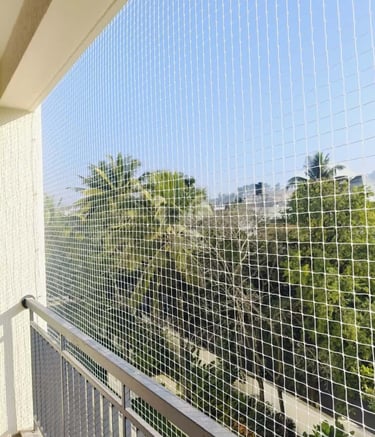 Technician carefully fitting a safety net on a balcony railing.