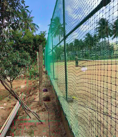 Technicians carefully fixing sports nets on a high-rise building rooftop in Bengaluru.