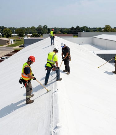 A high-quality action shot of a professional roofing crew in North American safety attire, working on a massive white TPO commercial roof installation during a bright day, emphasizing industrial scale and safety.