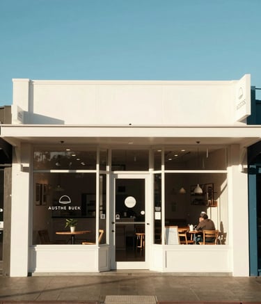 A bright and airy photograph of a local Australian cafe storefront in Perth during the morning. The scene is clean and inviting, with minimal signage and a friendly, professional atmosphere under a clear blue sky.