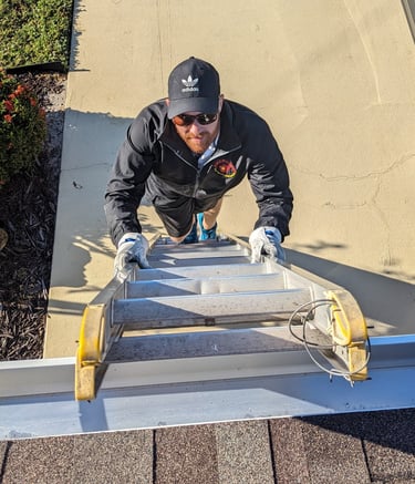 Ryan climbing a ladder to clean a roof vent in SE Cape Coral