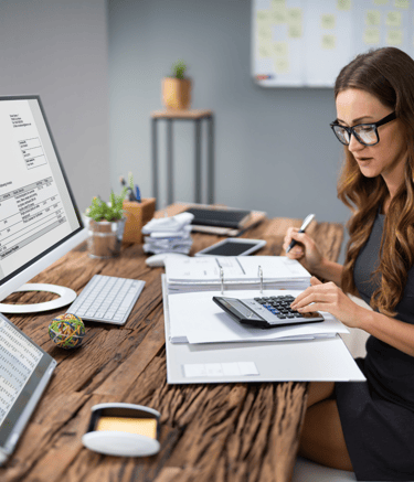 Une femme assise à son bureau, utilisant une calculatrice