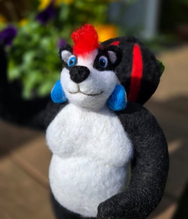 Handmade needle felted skunk figurine with a red mohawk and blue earrings in a garden setting.