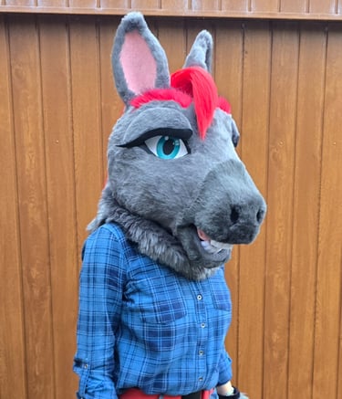 Grey horse fursuit head with red hair and blue eyes, worn with a blue plaid shirt.