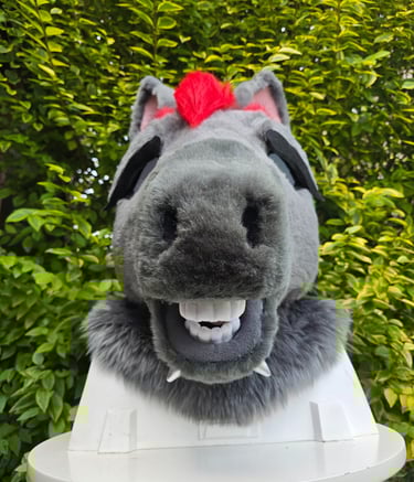 Custom grey furry horse head mask with red mohawk and realistic teeth displayed outdoors.