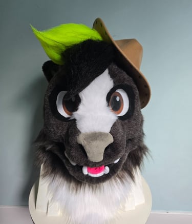 Custom furry skunk fursuit head featuring dark fur, neon green hair, and a brown cowboy hat.