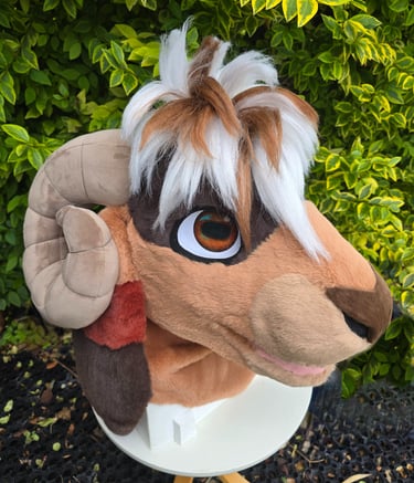 Handmade brown and white ram fursuit head with curved ram horns and faux fur mohawk.