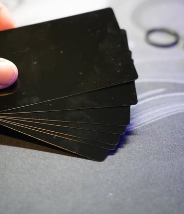 A hand holding a fanned deck of black playing cards on a grey gaming mat.