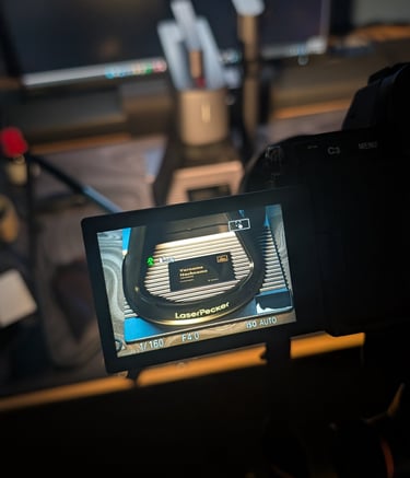Camera screen previewing a LaserPecker engraving machine setup in a dark home office studio.