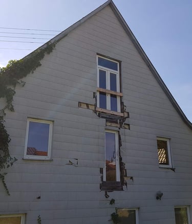 eine alter Fassade mit Löchern in der Verkleidung. Efeu rankt. 