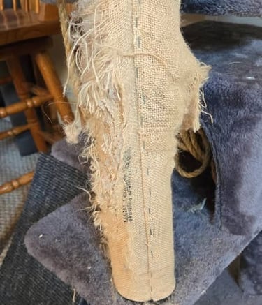Worn cat tree scratching post with shredded sisal fabric and frayed rope showing heavy use.