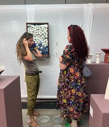 2 visitors listen to an audio installation, looking at a sculpture of Victorian ink bottles
