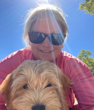 a woman in sunglasses and sunglasses is holding a dog