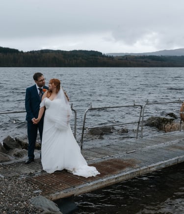 A bride and groom posing on a dock by loch venture 
