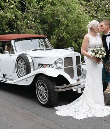 a bride and groom standing next to a car