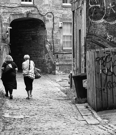 Two women, their back to camera, walk through Bread Street Lane, Edinburgh