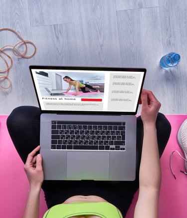 a woman sitting on a yoga mat with a laptop