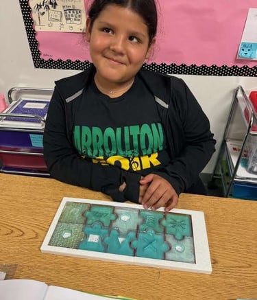 girl sits with a completed Braille Skills Puzzle in front of her, a look of pride on her face