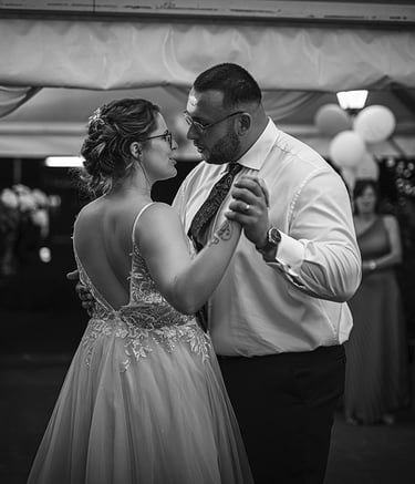 Ein Schwarz-Weiß-Foto eines Brautpaares, das bei seiner Hochzeit tanzt, wobei die Braut ein rückenfreies Kleid trägt und der 