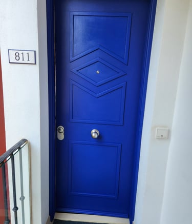 Modern vibrant blue front door with geometric panels and house number 811 on a white wall.