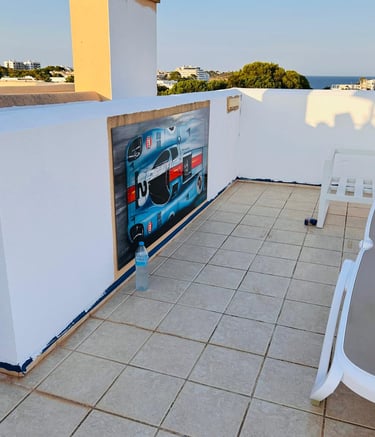Rooftop terrace featuring a racing car wall mural and a lounge chair with ocean views.