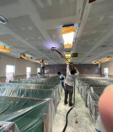 man preparing a ceiling to be painted with a sander in his hand.