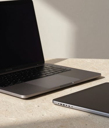 A close-up shot of a professional workspace featuring a sleek dark charcoal laptop and a high-end tablet. The setting is minimalist with a light beige stone surface and soft off-white walls. Natural, soft sunlight creates a professional and reliable atmosphere.
