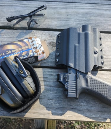 Eye and ear protection, self-defense ammunition, holstered self-defense firearm with red dot.