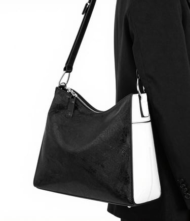 A brown leather handbag with a structured rectangular shape is prominently displayed. It features two handles and buckle accents on the front, highlighting a classic and elegant design. The stitching is visible along the edges, adding to the refined appearance.