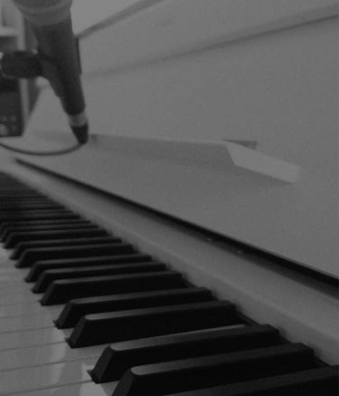 Close-up black and white shot of piano keys with a recording microphone in a music studio.