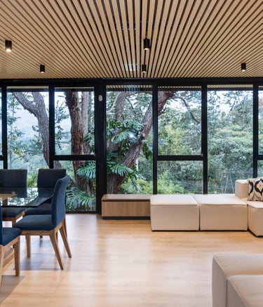 Interior moderno con ventanales de piso a techo y vista al jardín, iluminación cálida