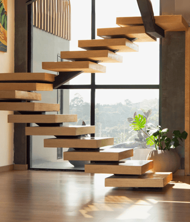 Escalera interior flotante de madera con estructura metálica y fondo acristalado.
