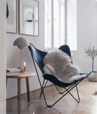 Zona de estar con decoración simple, un sillón moderno y mesita, tonos claros