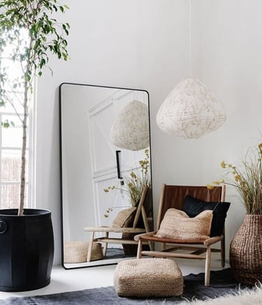 Interior de una habitación, con decoración minimalista, espejo, sofá, puff, lampara, alfombras