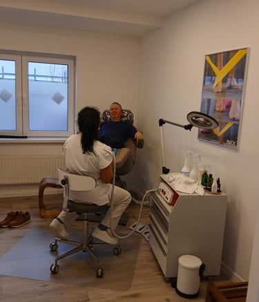 Professional podiatrist providing medical foot care to a patient in a bright podiatry clinic treatment room.