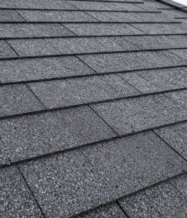 Close-up photography focusing on the texture and layered installation of high-quality architectural roofing shingles in Dark Slate Gray. Sharp detail, professional lighting, North American / US residential style.