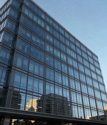A wide shot of a modern architectural office building with glass walls, reflecting a Sky Blue sky. The scene conveys reliability and scale. Clean lines and professional atmosphere. Spanish-speaking / Global city setting.