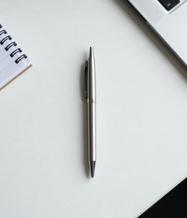 A minimalist top-down photo of a clean white desk surface with a single silver pen and a notebook. Soft daylight. Professional, North American / Texan office atmosphere.